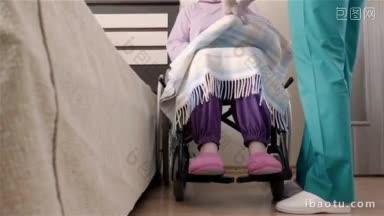护士帮助坐<strong>轮椅</strong>的老年残疾妇女把她放在家里或敬老院的床上慢动作